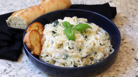 Speedy spinach fettuccine alfredo on plate with bread and glass of rose wine