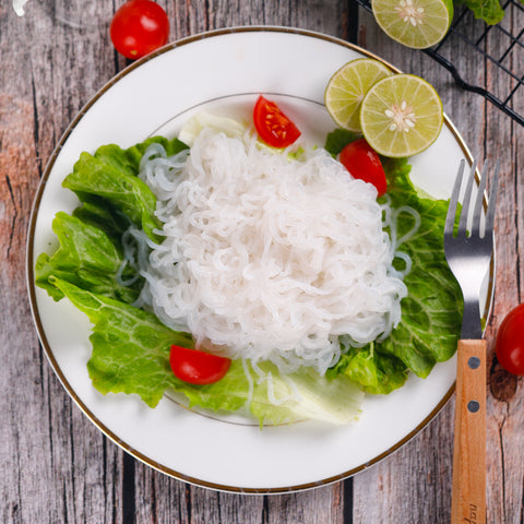 Plain, low carb, odorless, organic GoSkinny Noodles Angel Hair konjac noodles (shirataki) plated with greens, tomatoes, lime