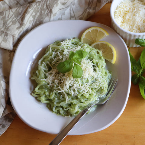 Cream Avocado Pasta featurning low carb Organic GoSkinny Noodles Spaghetti with lemon slices, beside small bowl of Parmesan and basil