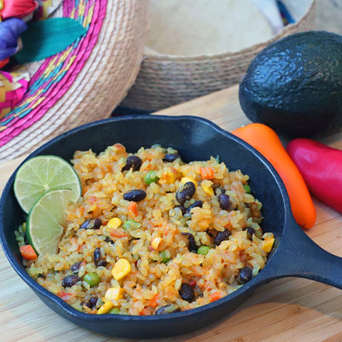 Spanish Rice in cast iron skillet made with organic, low carb GoSkinny Noodles Rice and lime wedges