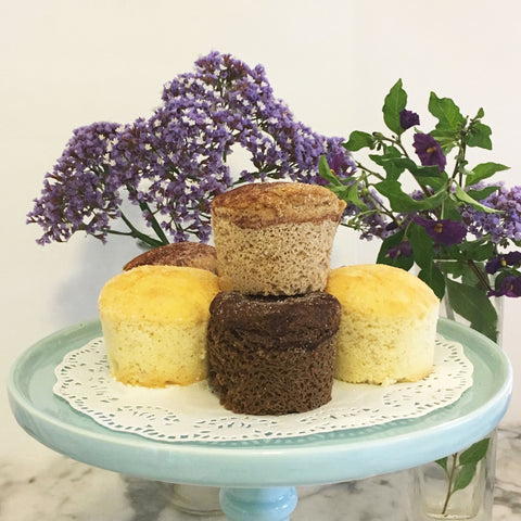 38-Calorie SmartCakes on cake platter with doily and flowers in background. Available in 5 delicious flavors: Lemon, Cinnamon, Chocolate, Raspberry Cream, and Vanilla Latte